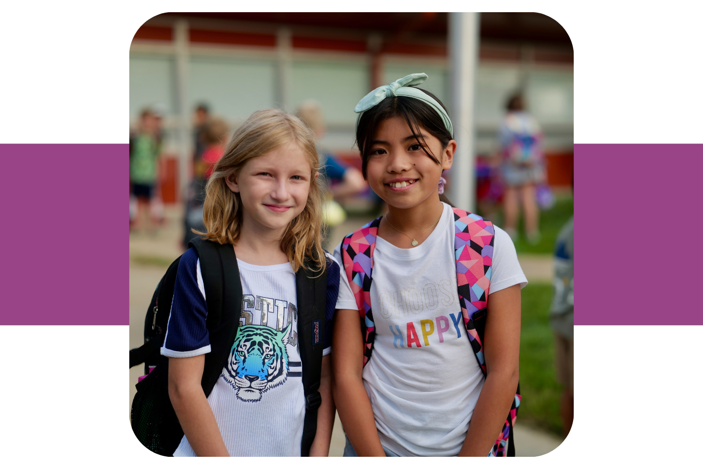 Two elementary aged girls pose together outside of school.