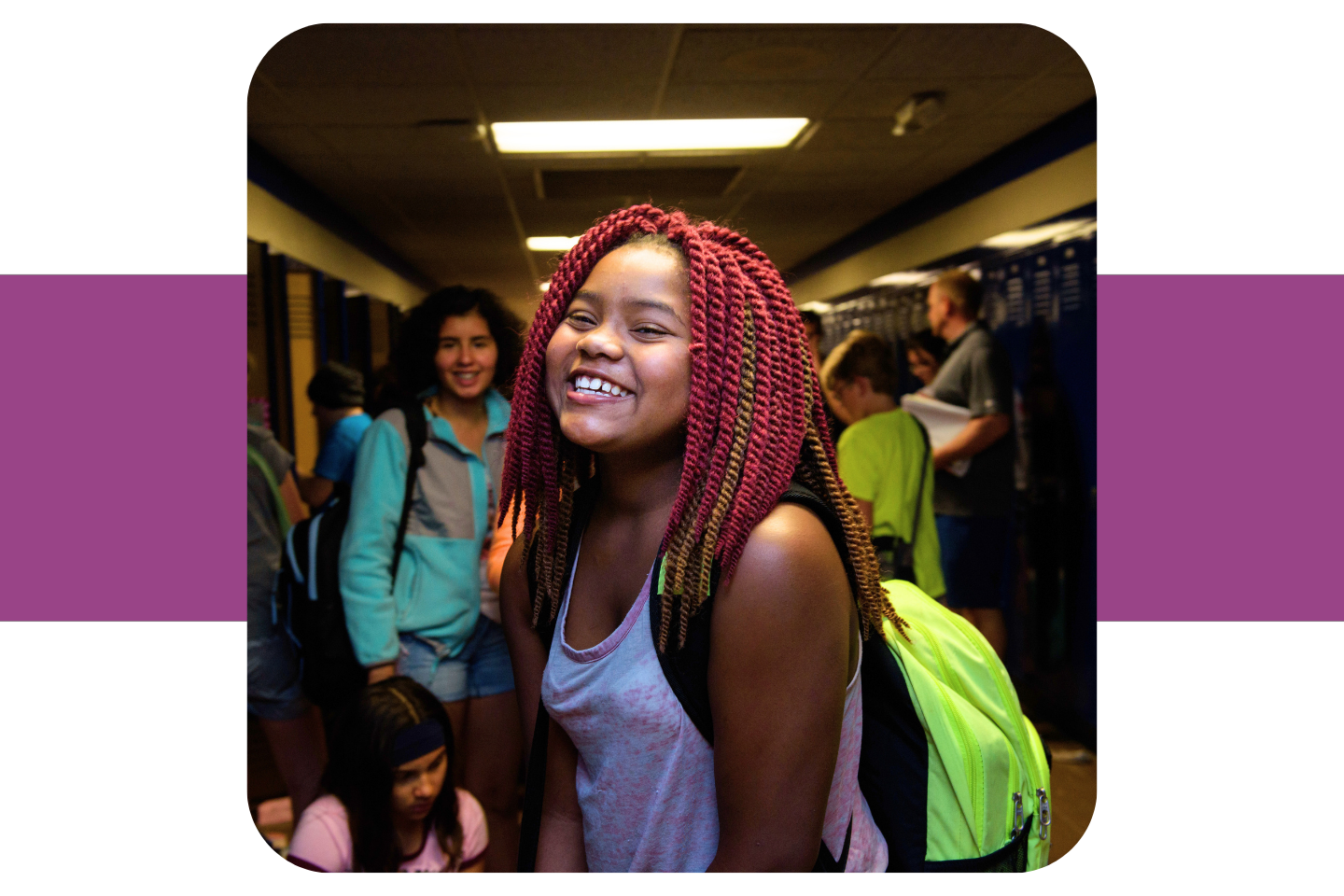 A middle school girl smiles in a crowded hallway.